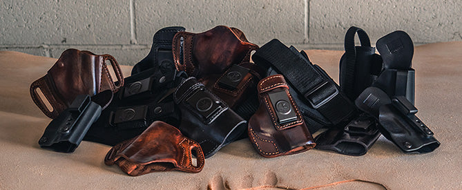 Pile of black and brown leather gun holsters